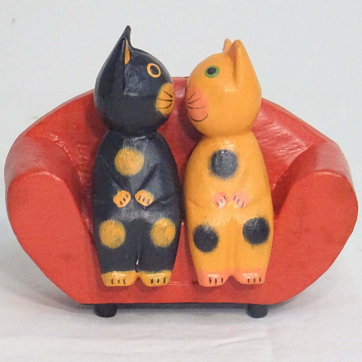 2 Canoodling Cats sitting on a red sofa